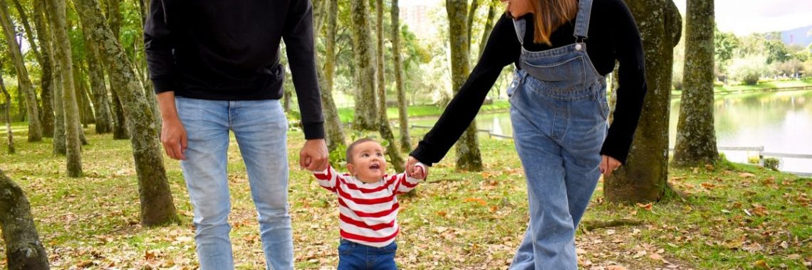 A joyful family enjoys a walk under lush green trees in the park.