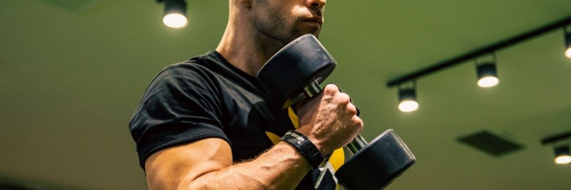 A man intensely lifting dumbbells indoors, showcasing strength and determination.